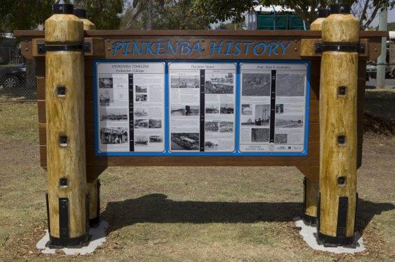 Photo of the Pinkenba Heritage Trail information board which is held up by large wooden poles and shows image and text descriptions